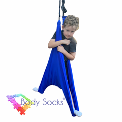 Child standing in a blue Lycra Therapy Swing.