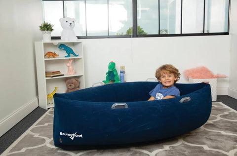 Child sitting in the 48" Comfy Hugging Peapod Sensory Pod in blue providing inflatable deep pressure seating with gentle rocking motion for emotional regulation, occupational therapy, sensory rooms, inclusive classrooms and home therapy.