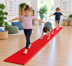 Three long red textured sensory walkway mats joined end-to-end, with children barefoot walking, balancing and crawling along the tactile pathway in an inclusive sensory play and therapy room.”
