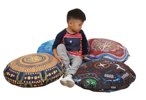 Child sitting with four Billyara and Charlie Wicking First Nations Round Cushions Set of 4 featuring authentic Indigenous artwork