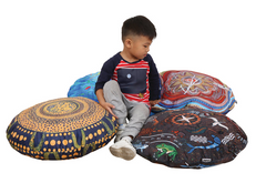 Child sitting with four Billyara and Charlie Wicking First Nations Round Cushions Set of 4 featuring authentic Indigenous artwork