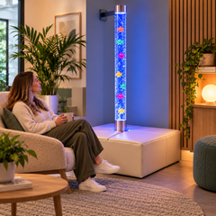 Adult relaxing beside a colour-changing bubble tube in a wellbeing space.