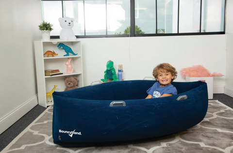 Child sitting in the 60" Comfy Hugging Peapod Sensory Pod in blue providing inflatable deep pressure seating with gentle rocking motion for emotional regulation, occupational therapy, sensory rooms, inclusive classrooms and home therapy.