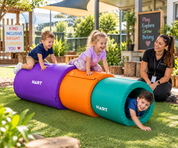Children enjoying HART Stack-A-Tubes sensory tunnels in an outdoor preschool play area.