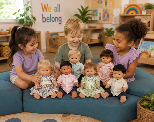 Three children sitting on a blue cushioned bench in a children's playroom, holding and playing with seven baby doll figures of different skin tones and outfits.