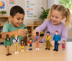 Two children playing with a set of small colorful toy figures on a wooden table in a bright classroom setting.