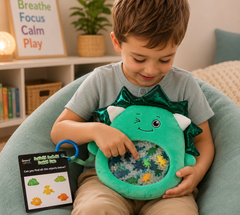 A smiling young boy explores the Sensory Seekers Danny Dino in a cosy sensory space, searching through colourful beads and hidden dinosaur shapes in the clear window while using the matching seek-and-find activity card.