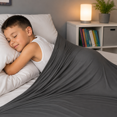 Child resting comfortably under a spandex sensory compression sheet designed to provide calming sensory feedback and gentle deep pressure.