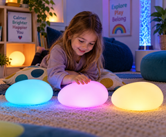 Child exploring three colour-changing LED sensory pebbles for calming and self-regulation.