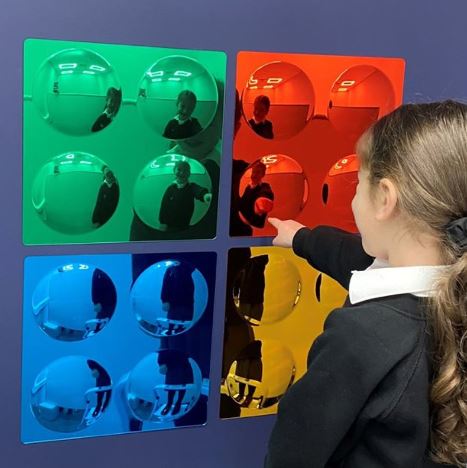 Child looking at set of 4 coloured bubble mirrors in green red blue and yellow