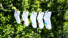 Pairs of different sized Dot On A Sock socks hanging on a line