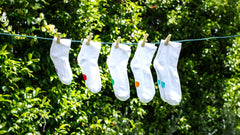 Pairs of different sized Dot On A Sock socks hanging on a line