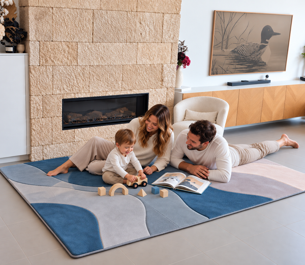 A couple with their young child enjoy play time on the Ocean Dune Designer Print Memory Foam Mat styled in a contemporary home to create a comfortable floor area for relaxation and everyday activities.