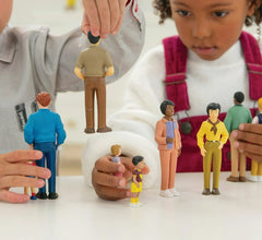 Small figurines of people arranged on a surface with a children interacting.