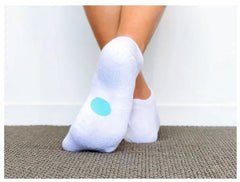 Legs of child wearing white Dot On A Sock ankle socks with aqua dot on soles