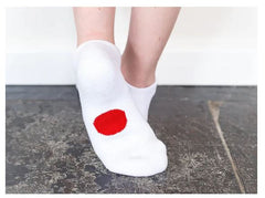 Legs of child wearing white Dot On A Sock ankle socks with red dot on soles