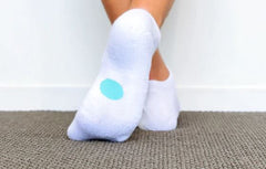 Legs of child wearing white Dot On A Sock ankle socks with aqua dot on soles