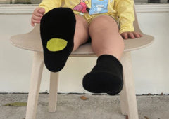 Little child's legs displaying yellow dot Dot on a Sock socks