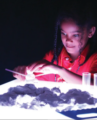 A young girl doing craft activities on a white lit Extra Bright Light Cube