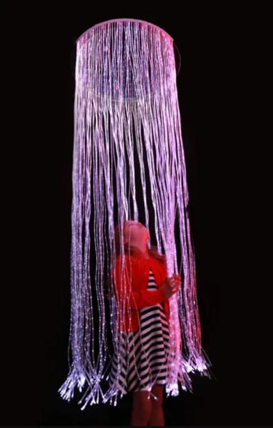 This is an image of a girl inside the sensory fibre optic Curtain ring + Adaptor. The girl is wearing a red cardigan over a black and white striped dress.