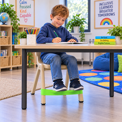 Child using a Fidget Chair Band with feet resting on the sensory band while seated at a classroom desk.