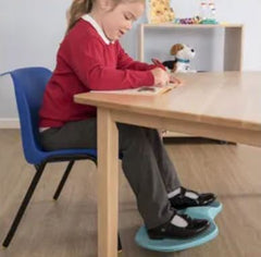 Child at desk using the Fidgety Feet board