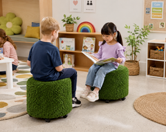 Aalto Round Grass Ottoman being used in a children's classroom reading corner, with two children seated on tactile grass-textured ottomans while reading together in a sensory-friendly learning environment.