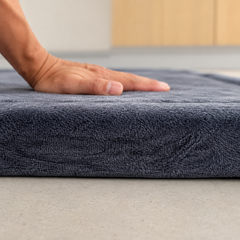 Hand pressing down on a dark grey memory foam mat.t