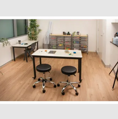 This is an image of two Ergerite Height Adjustable stools with castors and a desk in a learning setting.