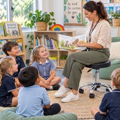 Teacher sitting on an Ergerite Height Adjustable Stool reading to children in a classroom.