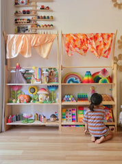 This is an image of the Wooden Interactive Play Stand and Retreat Den with colorful fabric and toys on the shelves. 