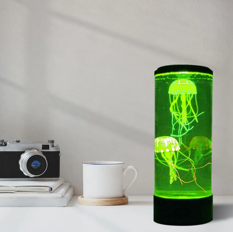 Desk setting with a green lit Jelly Fish Tank – Round Black with two realistic floating jellyfish, colour-changing LED lighting and quiet operation for sensory rooms, therapy clinics, classrooms, aged care settings and home environments.
