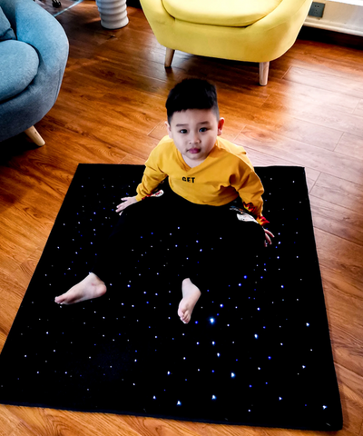 Child sitting on the LED Sensory Carpet 95cm with illuminated fibre optic strands providing calming visual stimulation for sensory rooms, occupational therapy, emotional regulation, inclusive learning and home therapy environments.