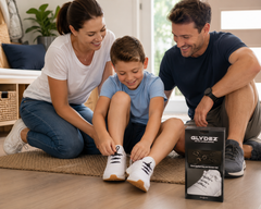 Child using GLYDEZ no-tie shoelaces with support from his parents at home.