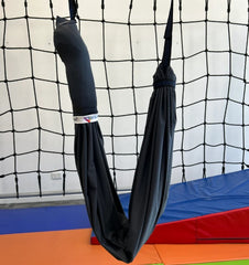 Unopened black layered therapy swing hammock suspended from the ceiling.