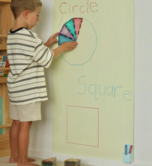 Young boy arranges magnetic shapes on a butter coloured Magnetic Chalk Wall Archway that encourages shape recognition and hands-on learning.