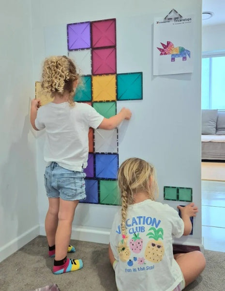 Children using a white coloured magnetic wall decal to arrange colourful magnetic construction tiles, supporting hands-on learning and creative exploration.