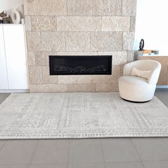 Sandstone beige memory foam mat displayed in a modern living room with a stone fireplace and cream accent chair.
