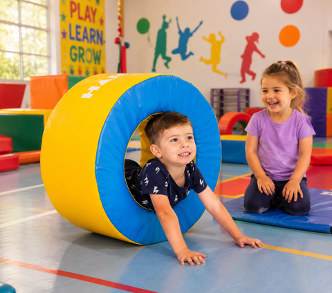 Children enjoying active play with a colourful Mini Tunnel in a school gym.