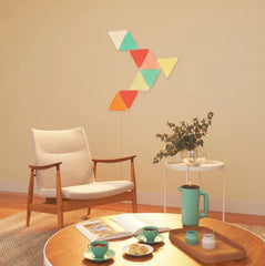 Image of a Nanoleaf triangle set of 9 tiles on a wall with a chair and table in the foreground.