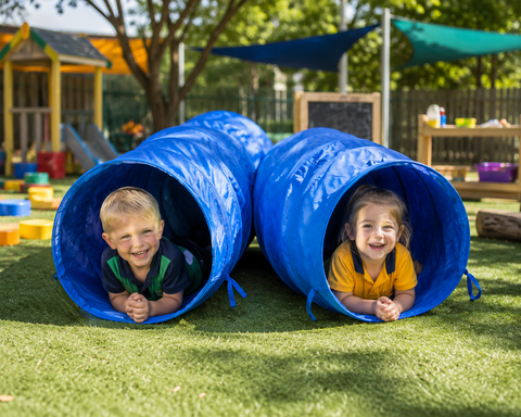 Children enjoying blue crawling tunnels in an outdoor preschool play area.