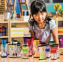 Child looking at an assortment of timers including the Ooze Tubes Visual Timer Set with four colourful slow-flowing liquid tubes for focus, emotional regulation, visual observation, therapy, classrooms, NDIS support and home use.