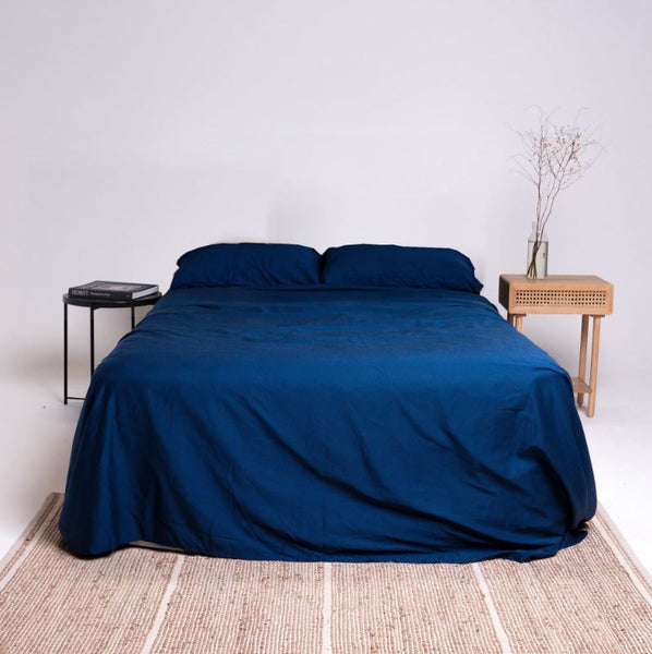 This is an image of a bed made with The Lad Collective™ Original Bedding Set and Fitted Sheets - Easy to Make Bed Linen. This colour is dark blue and is called Pacific.