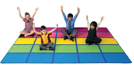 Four young students sitting on the Rainbow Blocks classroom seating rug 3m x 2m with colourful individual student seating squares in rainbow stripes for schools and early learning spaces .