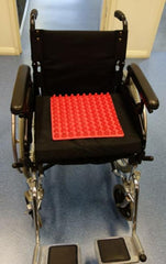 This is an image of the red Sensory_Feedback_Tactile_Square_Mat_ on a wheelchair seat.