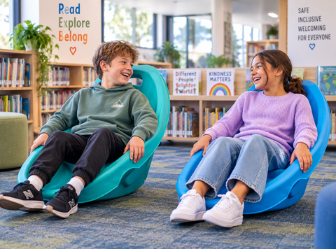 Two children using Rocking Floor Chairs in green and blue