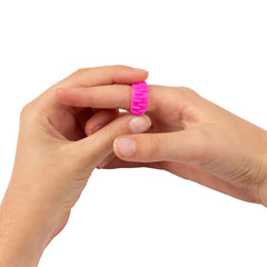 Hand wearing a pink silicone ring on a white background