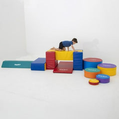 This is an image of a child climbing on a colourful balance kit made of foam and covered in vinyl.