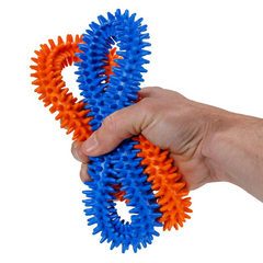 Adult hand squeezing two HART Spike Rings ideal for occupational therapy, movement and hand-eye coordination activities.