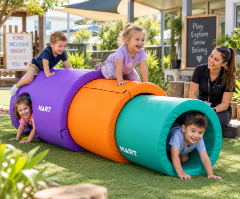 Children enjoying HART Stack-A-Tubes sensory tunnels in an outdoor preschool play area.